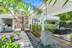 ヌーサヘッズにあるPeaceful & Stylish Retreat, Noosa Headsの石造りの家と椅子付きのパティオ