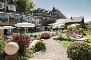 a resort with chairs and umbrellas and a pool at Ebner's Waldhof am See Resort & Spa in Fuschl am See