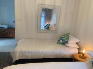 a small bedroom with a bed and a mirror at Sunrise on Main in Tairua