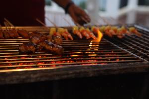 uma pessoa está cozinhando carne em uma grelha em PearlDrop Waves Mirissa em Mirissa