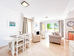 ein Wohnzimmer mit einem Tisch, Stühlen und einer Uhr in der Unterkunft Beach & Golf Apartment in Bahía de Casares in Bahia de Casares