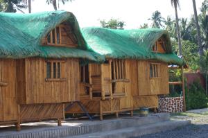 a large wooden house with a green roof at Hana-Natsu Resorts Pool & Hotel in Maybayo