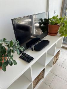 a tv on a white shelf with two remote controls at Bright And Airy Islington Apartment in London