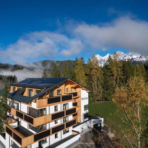 un edificio de apartamentos con montañas en el fondo en Waldrand Apartments en Ramsau am Dachstein