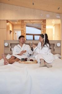 a man and woman sitting on a bed with food at Bella Lake Resort in Kuopio