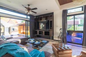 a living room with a couch and a tv at Thabali Oasis:3BHK private pool villa + Sauna in Pattaya South