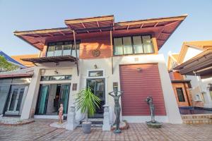 dom z czerwonymi drzwiami i dwoma posągami w obiekcie Thabali Oasis:3BHK private pool villa + Sauna w Pattaya South