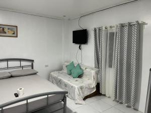 a bedroom with a bed and a chair and a tv at Nolina's Transient Rooms - Alaminos, Pangasinan in Alaminos