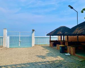 a beach with a fence and a building with a gate at Hana Natsu Resorts Beach & Hotel in Morong