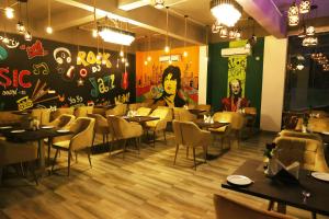 Hotel Golden Palm في باتنا: مطعم بطاولات وكراسي و لوحة على الحائط