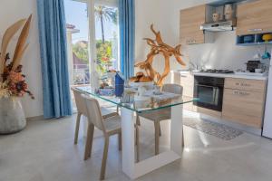 uma cozinha com uma mesa de vidro e cadeiras numa cozinha em Gerani Apartments em Bordighera
