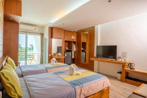 a hotel room with two beds and a television at Tamnanpar Resort in Ban Phe