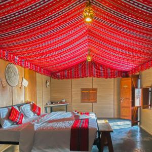 a room with a bed with a red canopy at SAMA Al Areesh Camp in Al Qābil