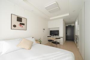1 dormitorio con cama blanca y escritorio en Urbanstay Dangjin Terminal, en Dangjin