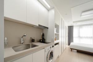 a white kitchen with a sink and a dishwasher at Urbanstay Dangjin Terminal in Dangjin