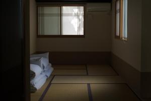 a room with a window and a bed with white pillows at Guesthouse ZenNichi in Kyoto