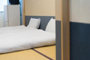 a bedroom with a bed with white sheets and pillows at Guesthouse ZenNichi in Kyoto