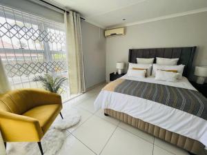 a bedroom with a bed and a chair and a window at musgrave manors villa in Durban