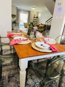 a wooden table with plates and glasses on it at musgrave manors villa in Durban +4 photos