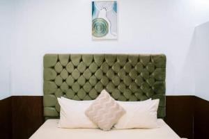 a bed with a green padded headboard and white pillows at Arka's Elegant Condos in Zamboanga