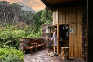 Cape Town的住宿－坎普斯灣度假酒店，站在有长凳的建筑物外的妇女