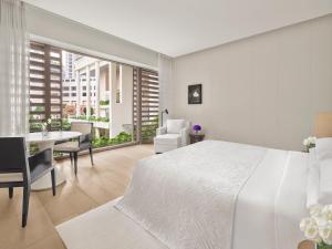a white bedroom with a white bed and a dining room at The Singapore EDITION in Singapore