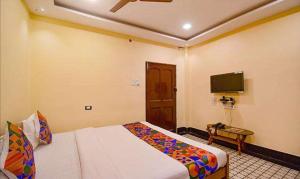 ein Hotelzimmer mit einem Bett und einem TV in der Unterkunft FabExpress Golden Imperial in Taliganja