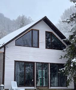 ein weißes Haus mit Glasfenstern im Schnee in der Unterkunft Sonna in Podzakharychi