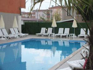 a swimming pool with chairs and a group of umbrellas at Koc Hotel in Karasu