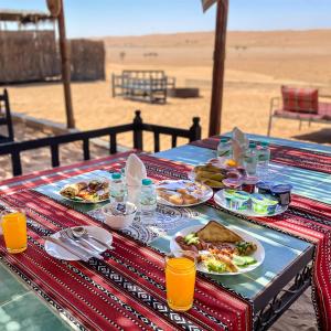 a table with plates of food on top of a beach at SAMA Al Areesh Camp in Al Qābil