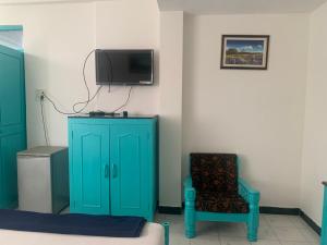 Pokój z niebieską szafką, krzesłem i telewizorem w obiekcie Shangrila by Craftels w mieście Majorda