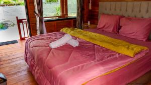 1 cama con edredón rosa y 2 almohadas en Mandalika Queen Hostel, en Kuta Lombok
