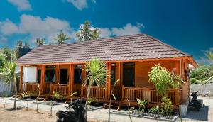 a wooden cabin with a porch and some palm trees at Mandalika Queen Hostel in Kuta Lombok