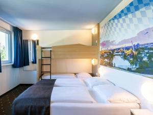 a bedroom with three beds and a painting on the wall at B&B Hotel München City-Nord in Munich