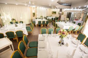 a banquet room with white tables and green chairs at Suior Resort Baza in Baia-Sprie