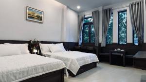 a bedroom with two beds and two windows at Huy Hoàng Hotel in Phan Thiet
