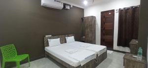 a bedroom with a bed and a green chair at SAN BEACH RESIDENCY in Karaikal