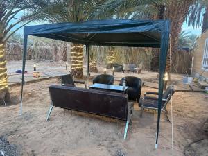 a blue tent with chairs and a table under it at كوخ ريفي داخل مزرعه in Madain Saleh