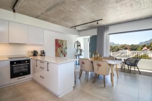 een keuken met witte kasten en een tafel en stoelen bij Luxury Escape at Alphen Glen Constantia in Kaapstad