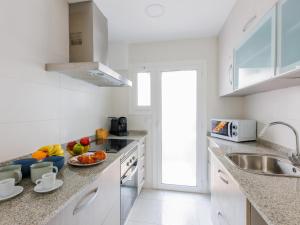 - une cuisine blanche avec évier et fruits sur le comptoir dans l'établissement matarolux25, à Mataró