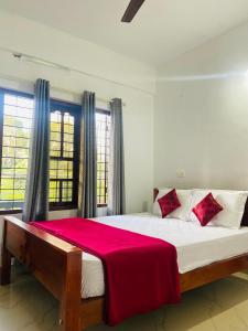 a bedroom with a large bed with a red blanket at Green Line Homestay in Vythiri