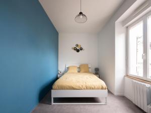 a bedroom with a blue accent wall and a bed at Aux Lilas - Hyper Centre - Wifi - 5 personnes - Rêve au Mans in Le Mans