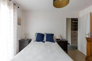 a bedroom with a large white bed with blue pillows at Cassiopée - Jacuzzi - Unique - 8p - Rêve au Mans in La Bazoge