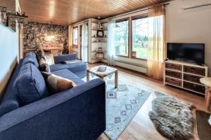 ein Wohnzimmer mit einem blauen Sofa und einem TV in der Unterkunft Minnebo stuga in Hässleholm