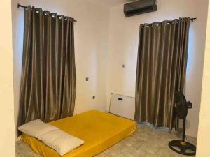 Schlafzimmer mit gelbem Bett und Vorhängen in der Unterkunft 4 Bedroom Apartment Available in Uyo