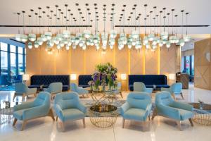 een lobby met stoelen, een tafel en een kroonluchter bij Maani Muscat Hotel & Suites in Muscat