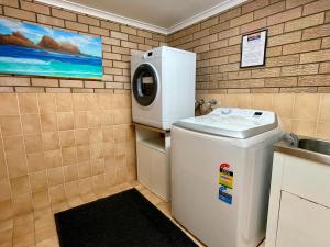 una pequeña cocina con lavadora y fregadero en Ocean View Motor Inn Merimbula en Merimbula