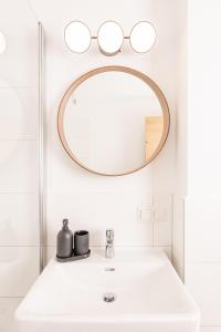 uma casa de banho com um lavatório branco e um espelho redondo em Apartment - Lärchenhof em Mauterndorf