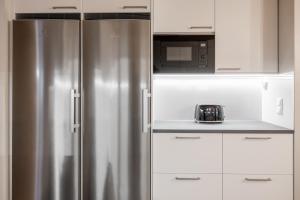 a stainless steel refrigerator in a kitchen with white cabinets at Arctic Holiday Apartments 5 in Rovaniemi