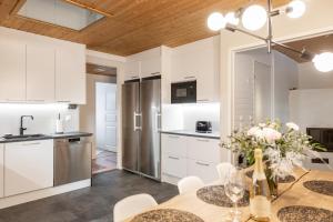 a kitchen with white cabinets and a wooden ceiling at Arctic Holiday Apartments 5 in Rovaniemi